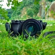 black sony dslr camera on green grass in front of brown and green mountain