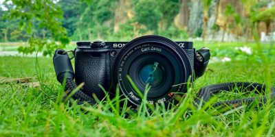 black sony dslr camera on green grass in front of brown and green mountain